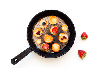 American pancakes with strawberries in authentic frying pan on white background. National pancake Day or Tiny pancake cereal.