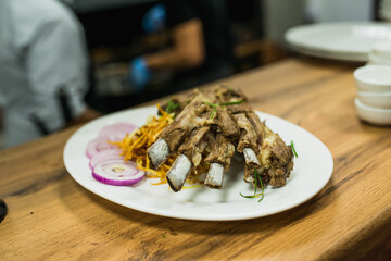 grilled lamb ribs on a white plate with a side dish