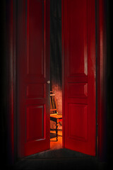 empty chair in light behind red massive vintage doors indoor. Old fashioned interior concept 