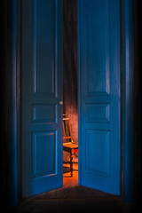empty chair in light behind blue massive vintage doors indoor. Old fashioned interior concept 