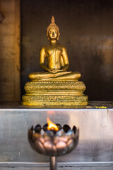 candles at a temple with a golden buddha in background, thailand