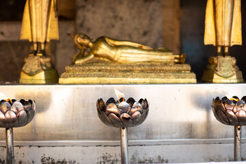 candles at a temple with a golden buddha in background, thailand