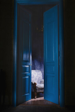 empty armchair in light behind blue massive vintage doors indoor. Old fashioned interior concept 