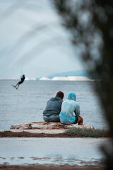 Image of a man kitesurfing while a father and son watch him in the distance