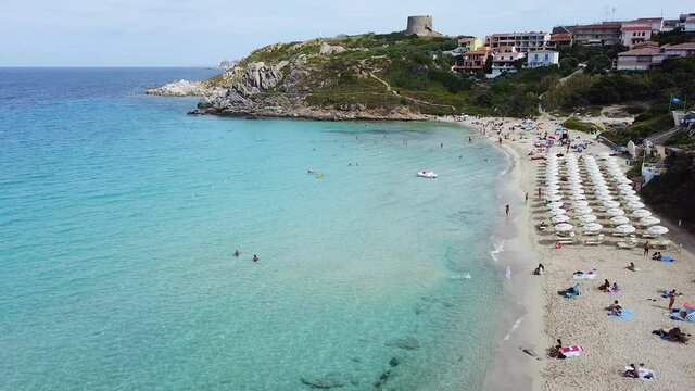 High view of Rena bianca beach, white umbrellas and white sand. View of tower of Santa Teresa di Gallura, Italy. 9 September 2020