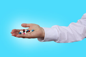 doctor, nurse, pharmacist in a white uniform holds a handful of multi-colored pills in his hands, the concept is pharmacological, medical