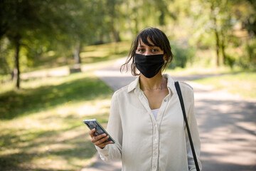 young woman protecting herself of covid with a mask in a park