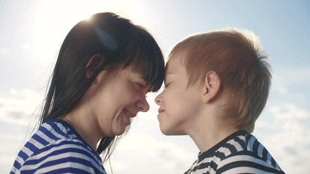 son and mom cute video concert mother's day. teamwork happy family boy kisses mother on the cheek touches his nose. parent takes care of lifestyle the child. kid and adult woman mom in the sunlight at