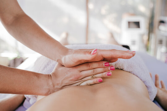Close-up of female therapist giving back massage to woman relaxing in health spa