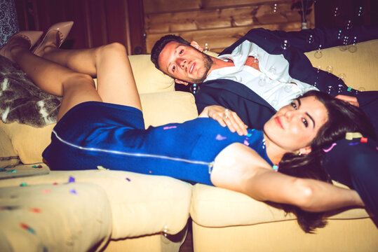 Young woman resting with handsome man on sofa in party