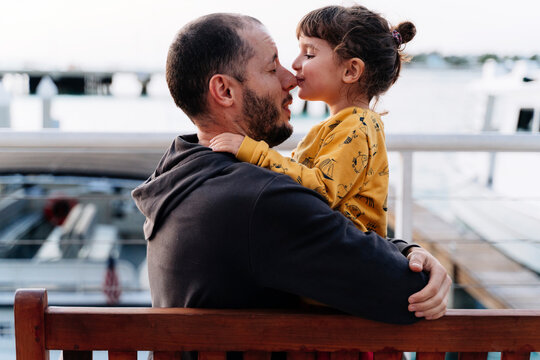 Father embracing while daughter kissing him on nose in city