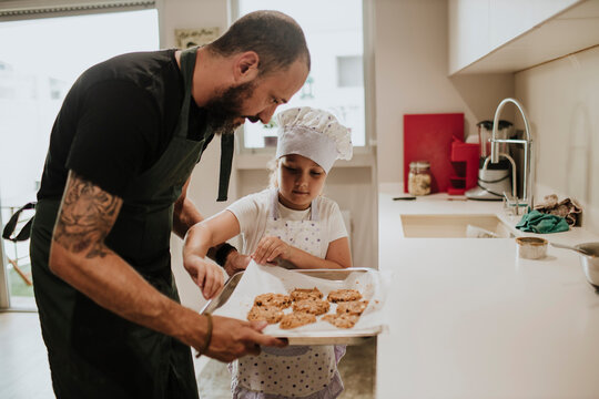 Father and daughter baking cookies at home