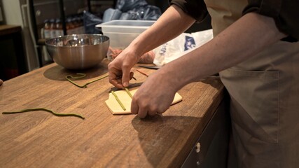 Male hands preparing italian food, process of ravioli making at the restaurant kitchen. Dough and ingredients for ravioli preparation, middle shot no face