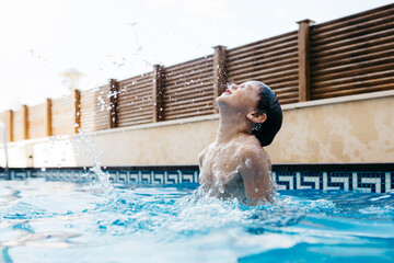 Playful boy swimming in pool during summer