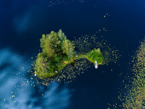 Aerial view of boat left on shore of small green islet on Vuoksi river