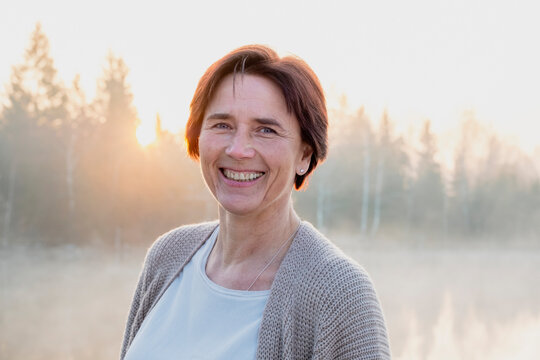 Portrait of adult woman smiling at camera during foggy sunrise