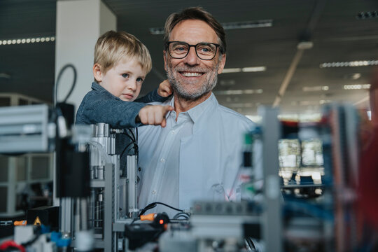 Scientist father showing machinery to son in laboratory at factory