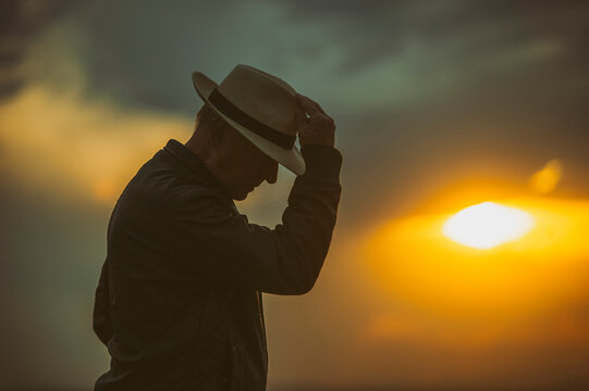 Senior man bowing in front of setting sun