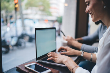 Unrecognizable man using smartphone and female worker typing on laptop