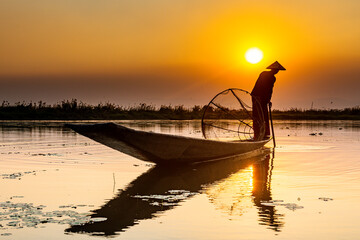 Myanmar, Shan state, Silhouette of traditional Intha fisherman on Inle lake at sunset