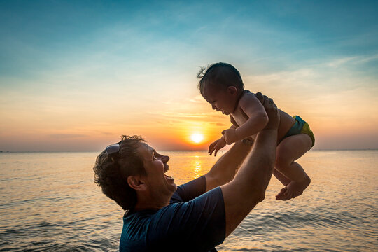 Vietnam, Phu Quoc island, Ong Lang beach, Father holding baby in beach at sunset