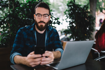 Fototapeta premium Smiling man using smartphone in cafe
