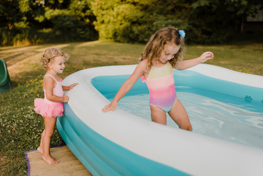 Two girls at inflatable swimming pool in garden