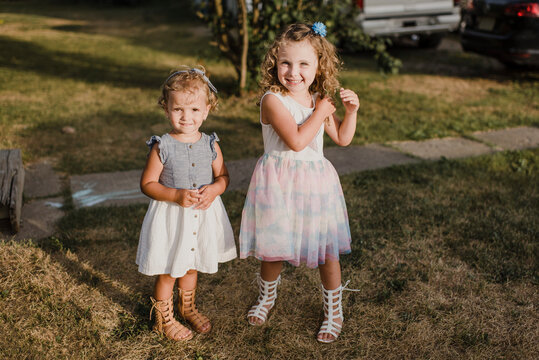 Portrait of two cute sisters standing on a meadow