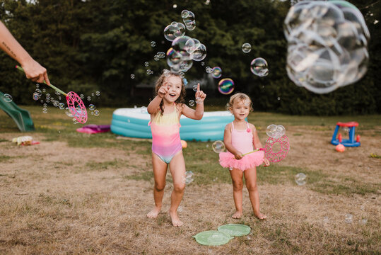 Two happy girls playing with soap bubbles in garden