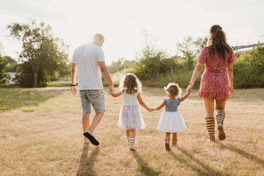 Family Walking On A Meadow In Backlight