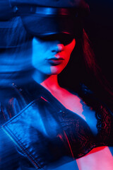 stylish portrait of a young girl in a leather jacket and cap with neon light