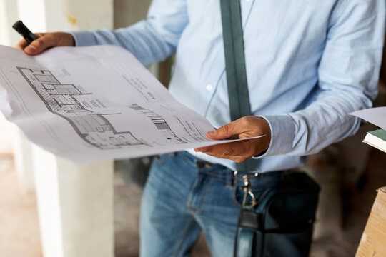 Architect holding plan in a house under construction
