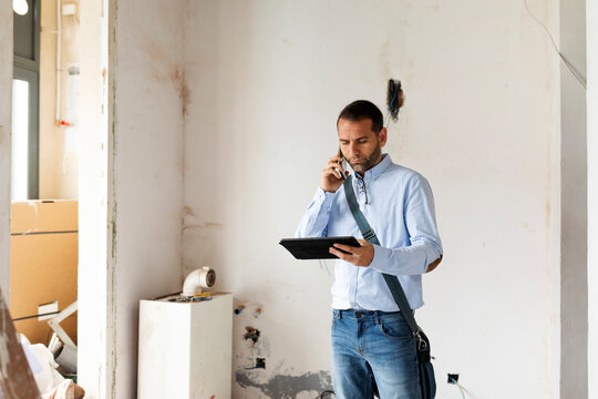 Architect with tablet on the phone in a house under construction