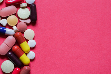 heap of tablets and capsules in pink background with space for text