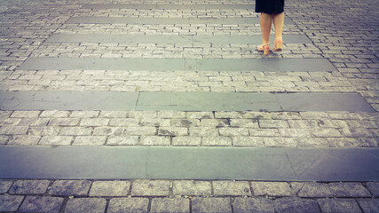 Girl's foot crossing a pedestrian crosswalk made of stones. Paved path. Cross the road for safety reasons when people cross the street on foot.