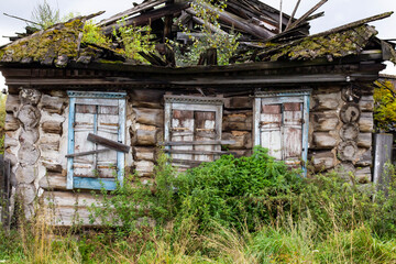 An old abandoned house made of logs, the roof collapsed. The concept of destruction and antiquity.