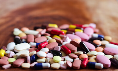 pile of medicine pills tablets capsules in wooden background