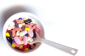 bowl of medicine pills tablets capsules in white background