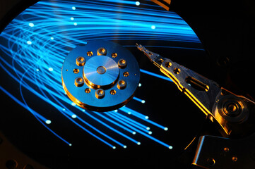 closeup of computer open hard disk drive with colored fiber optic reflected