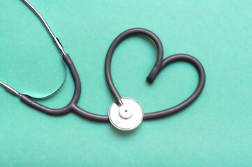 Stethoscope in Shape of Heart Isolated On Green Background.