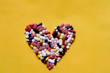 Medicine pills tablets capsules in shape of human liver in yellow background with space for...