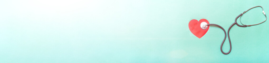 Stethoscope and red heart on green background. Top view. Banner. Copy space. Place for text.