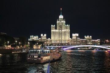Naklejka premium Colorful panorama of the night city with neon lights. Bridge over the river against the background of historic buildings at night
