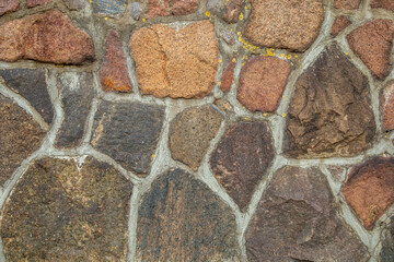 A wall made of a large old stone with sprouted moss from old age.