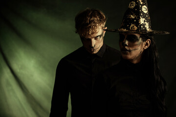 Couple in love with dark skull makeup on black background. Halloween face art
