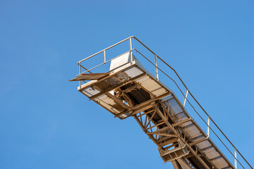 Fototapeta na wymiar Conveyor belt for gravel against the blue sky at an industrial cement plant.