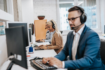 Handsome male customer service agent with headset working in call center.