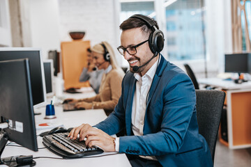 Handsome male customer service agent with headset working in call center.