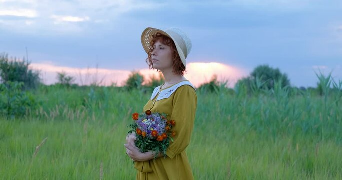 Young redhead woman with freckles in vintage handmade dress walk in fields with flowers