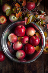 Red apples in a plate with water on a wooden background